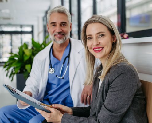 Two doctors looking at the camera with a sheet in their hands